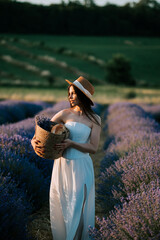 Woman in white dress holding lavender bouquet in blooming field at sunset