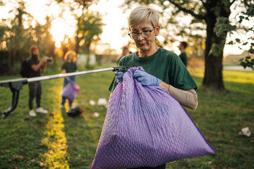 Senior female volunteer picking up trash in park