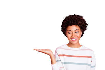 Photo of pretty dark skin wavy lady holding on open palm new cheap product advising buyers wear striped pullover isolated pastel pink color background