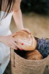 Freshly baked bread in a wicker basket with lavender flowers outdoors during a sunny day