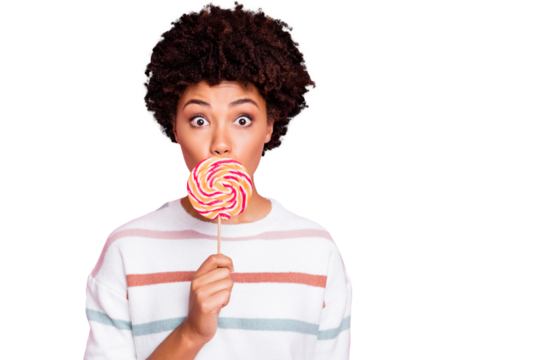 Photo of pretty dark skin wavy lady holding big round lollipop on stick hiding mouth keeping silence wear striped pullover isolated pastel pink color background