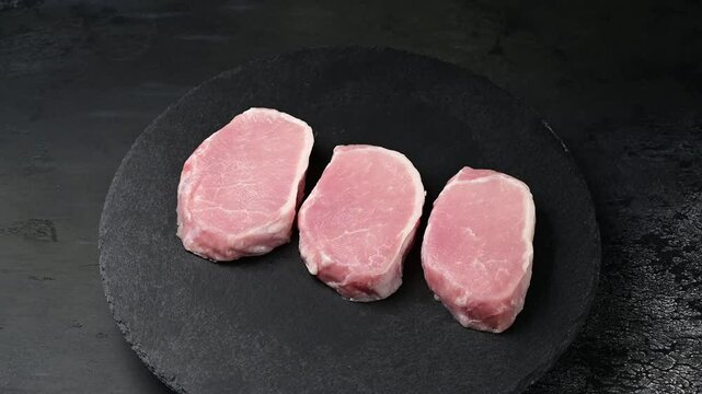 Sizzling transformation: raw pork escalopes arranged on dark slate surface