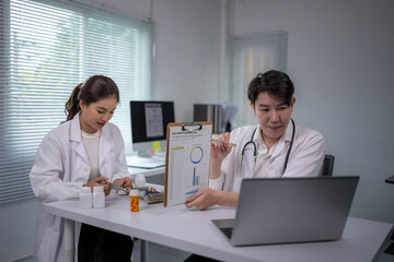 Fototapeta premium Two doctors are sitting at a desk with a laptop open in front of them