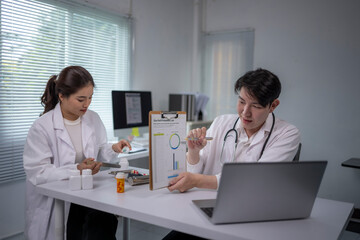 Fototapeta premium Two doctors are sitting at a desk with a laptop open in front of them