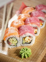 A sushi roll with avocado and shrimp on a wooden board