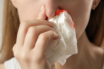 Nosebleed, a young woman with a bloody nose. Healthcare and medical concept. Close up studio image.
