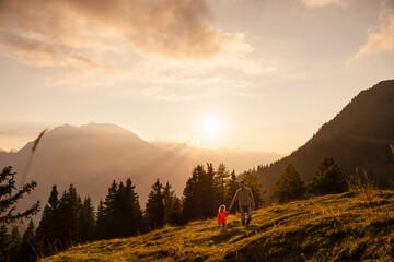 Man holding daughter's hand walking on grass