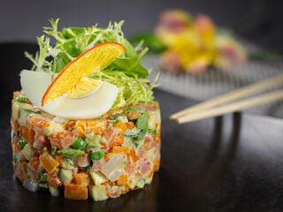 A colorful salad with a yellow egg on top