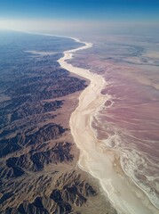 Low-altitude aerial shot showing  Desert's white lake with pink salt, mountains, rivers and ripples.