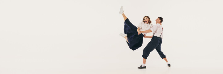 Two people performs an energetic lindy hop dance with dynamic poses against a white studio...