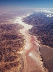 Low-altitude aerial view of Desert's white lake with pink salt, mountains, rivers and ripples.