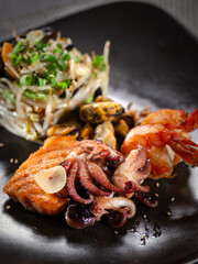 A plate of sea food with a piece of meat and a piece of fish