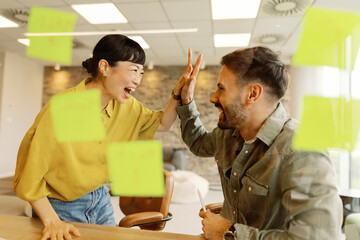 Two people celebrating with a high five in an office setting