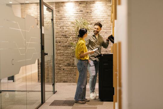 Coworkers using a copy machine in a modern office setting