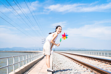 Asian woman playing pinwheel at outdoors enjoy moment with inner child blue sky background