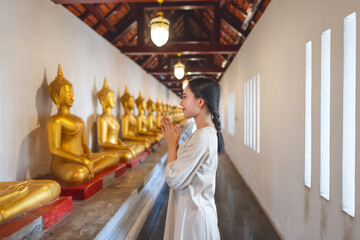 Buddhism religion woman put your hands together in a prayer position at temple with buddha statue, Thailand