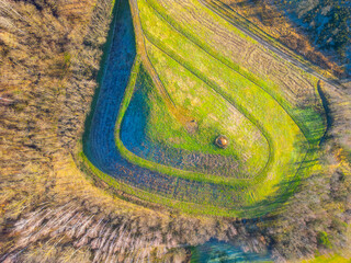 An aerial perspective shows a meticulously shaped artificial hill surrounded by lush greenery. The...