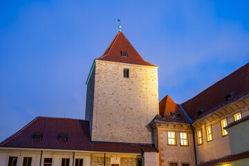 Fototapeta premium The Black Tower of Prague Castle stands majestically under the night sky, illuminated by warm street lamps. Its historical architecture offers a glimpse into Prague's rich heritage and beauty.