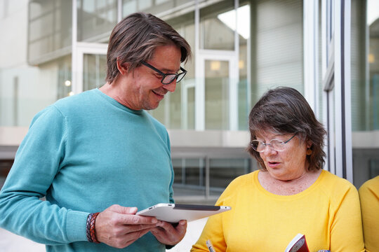 Elderly teacher and student learning outside classroom