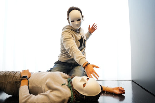 Teenagers in masks performing in drama class