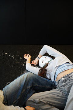 Teenagers in drama class with masks lying on stage