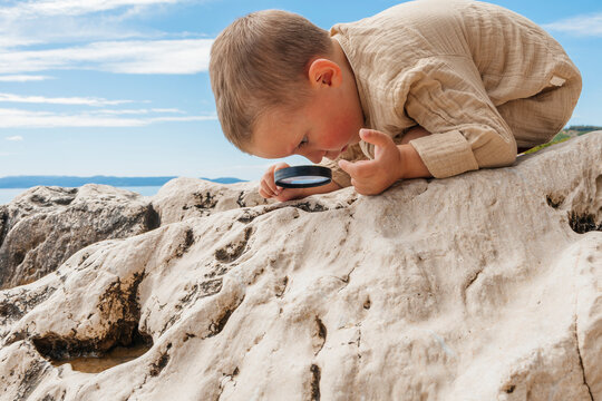 Child exploring rocks with a magnifying glass at the beach