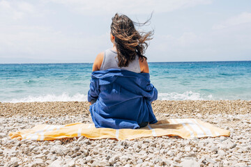 Woman relaxing on rocky beach with sea view