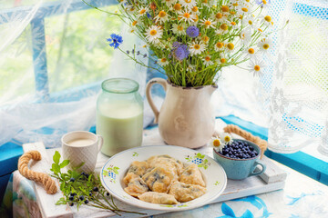 Homemade blueberry dumplings, wild forest berries, and fresh cow's milk served on a rustic wooden...