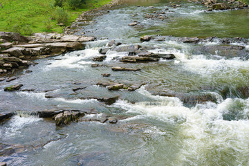 Dynamic image of a fast flowing mountain waterfall, rapid river crashing over mossy rocks. Energy...