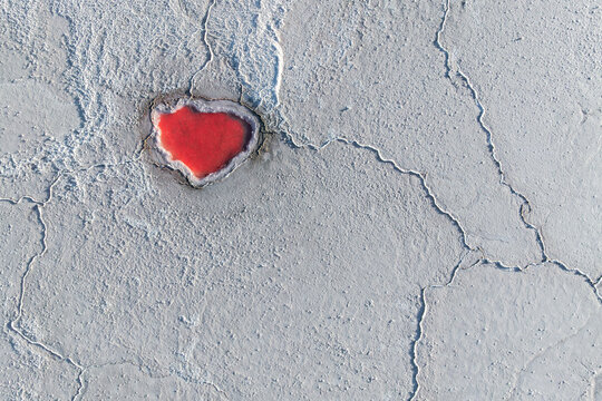 Red salt pond on cracked landscape in La Puna