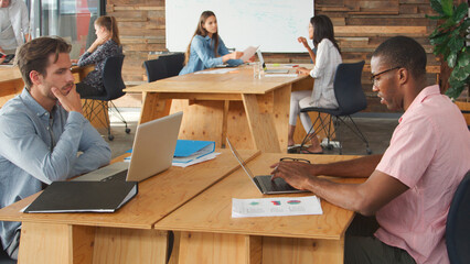 Business Team Using Laptops Hot Desking In Modern Office