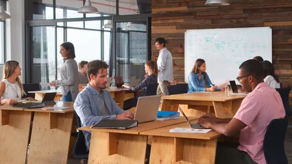 Fotobehang Business Team Sitting At Desks In Open Plan Office Working At Laptops © Monkey Business