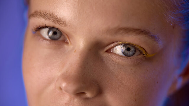 Fototapeta Closeup of a woman's eyes with artistic makeup and a blue lighting background. Concept of creative beauty and artistic expression in modern makeup trends.