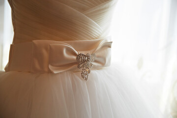 A white dress with a bow on it. The bow is made of crystals and is on the waist of the dress