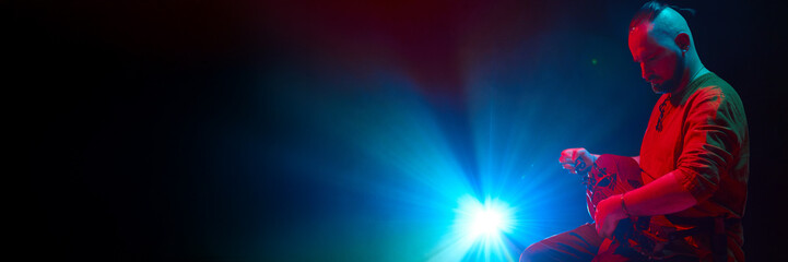 A musician plays an hurdy-gurdy under vibrant stage lighting effects. Concept of live musical...