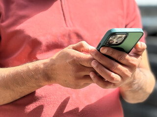 A man checking social media, texting on his smartphone to friends. Close-up image of a man using his smartphone, playing a mobile game or watching a video online while relaxing. People and technology.