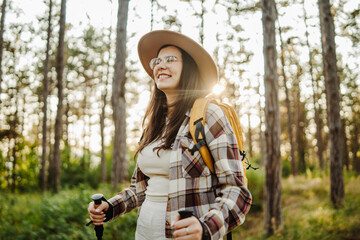 Young caucasian woman exploring scenic forest with hiking sticks and gear