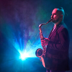 A saxophonist performs on stage, enveloped in colorful lights and swirling smoke. Concept of...