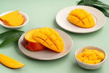 Fresh ripe mango with cubes on green table background.