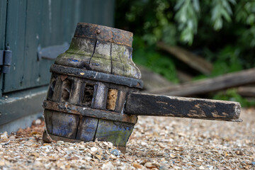 Old damaged wooden cogwheel with metal rim and weathered handle