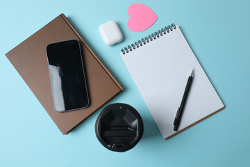 blank notepad with clock, alarm clock and pen on blue pastel pink background.