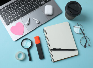 laptop glasses coffee headphones notepad on a blue background with space for text