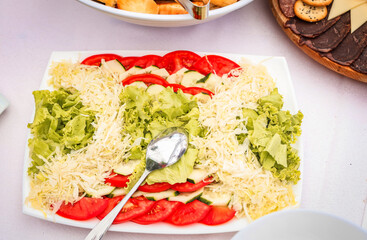 Fresh mixed salad with cabbage, tomatoes, lettuce and cucumbers served on a white platter during a festive lunch or catered event. Clean, natural, healthy food.