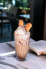 Tiramisu iced coffee with cream and ladyfinger biscuits on marble table