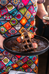 Chef holding brownie waffle with caramel, ice cream and strawberries