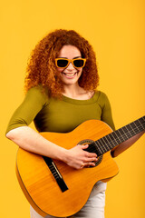 Redhead musician playing acoustic guitar on yellow background