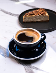 Mocha black coffee with hazelnut cheesecake slice on marble table