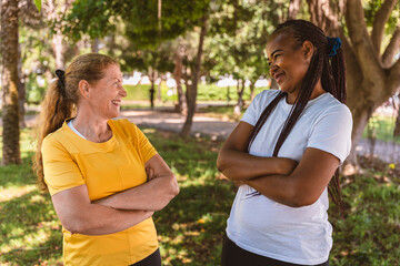 Obraz premium Senior friends standing close together in park, embracing, smiling warmly, demonstrating strong connection and companionship