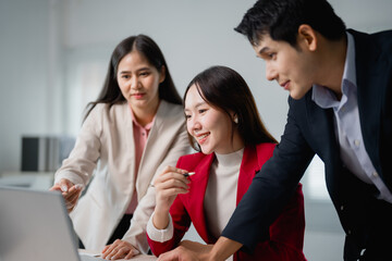 Three Asian businesspeople collaborating in a modern meeting room, discussing strategies for a new project while using a laptop, fostering teamwork and innovation