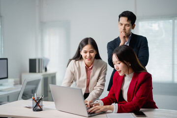 Three asian businesspeople are working together using a laptop in a modern office, discussing a project and collaborating effectively as a team
